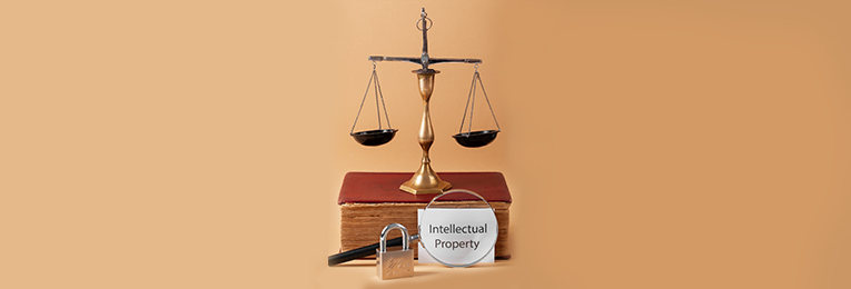 An image featuring a weight balance placed on a law book, with a magnifier highlighting the words 'Intellectual Property,' and a lock positioned next to them.